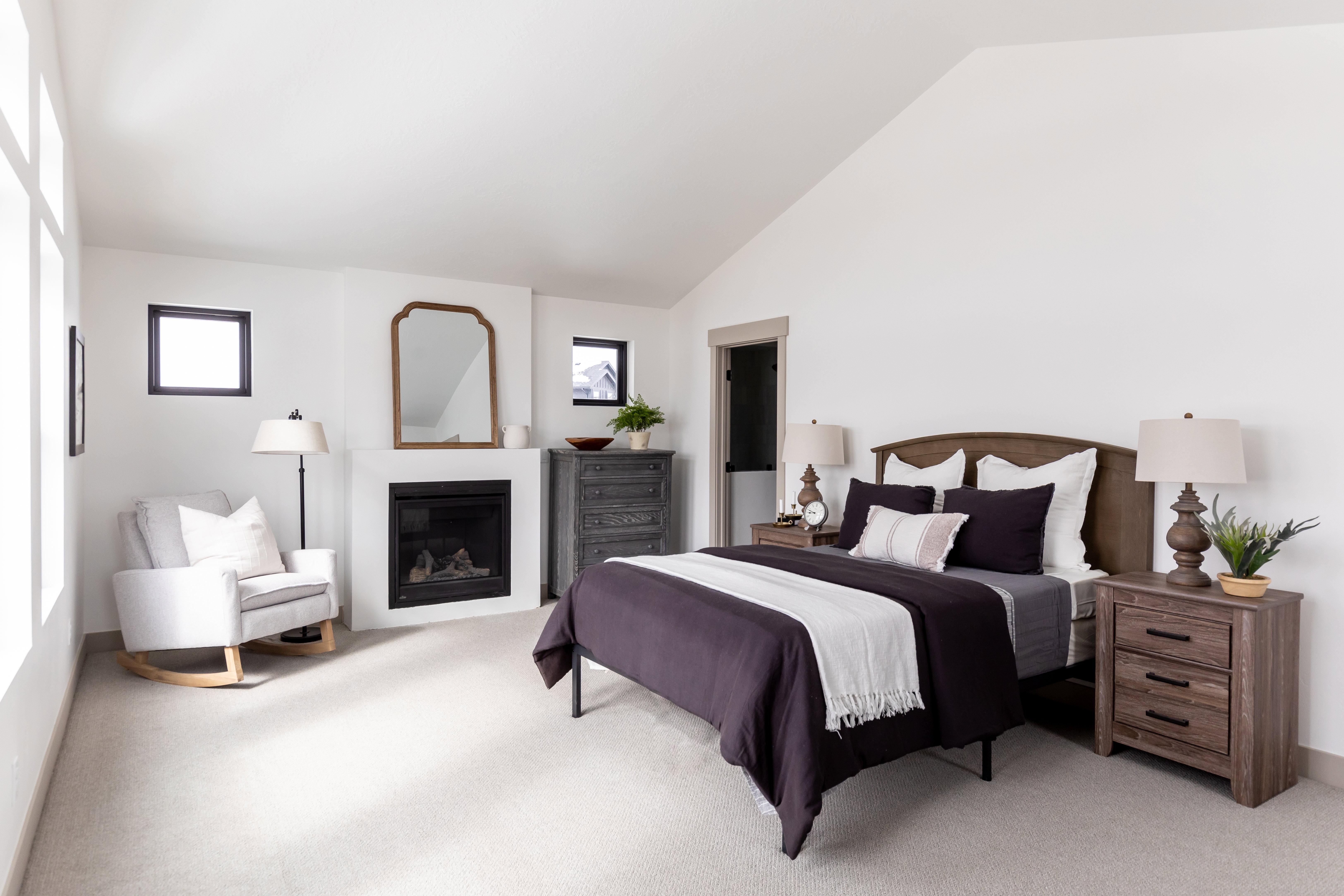 Bedroom with a glass covered fireplace, lofted ceiling, and light carpet