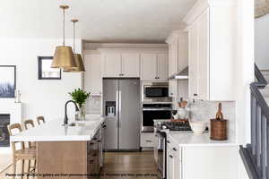 Dual tone kitchen featuring a breakfast bar area, stainless steel appliances, light stone countertops, backsplash, and dual tone cabinets