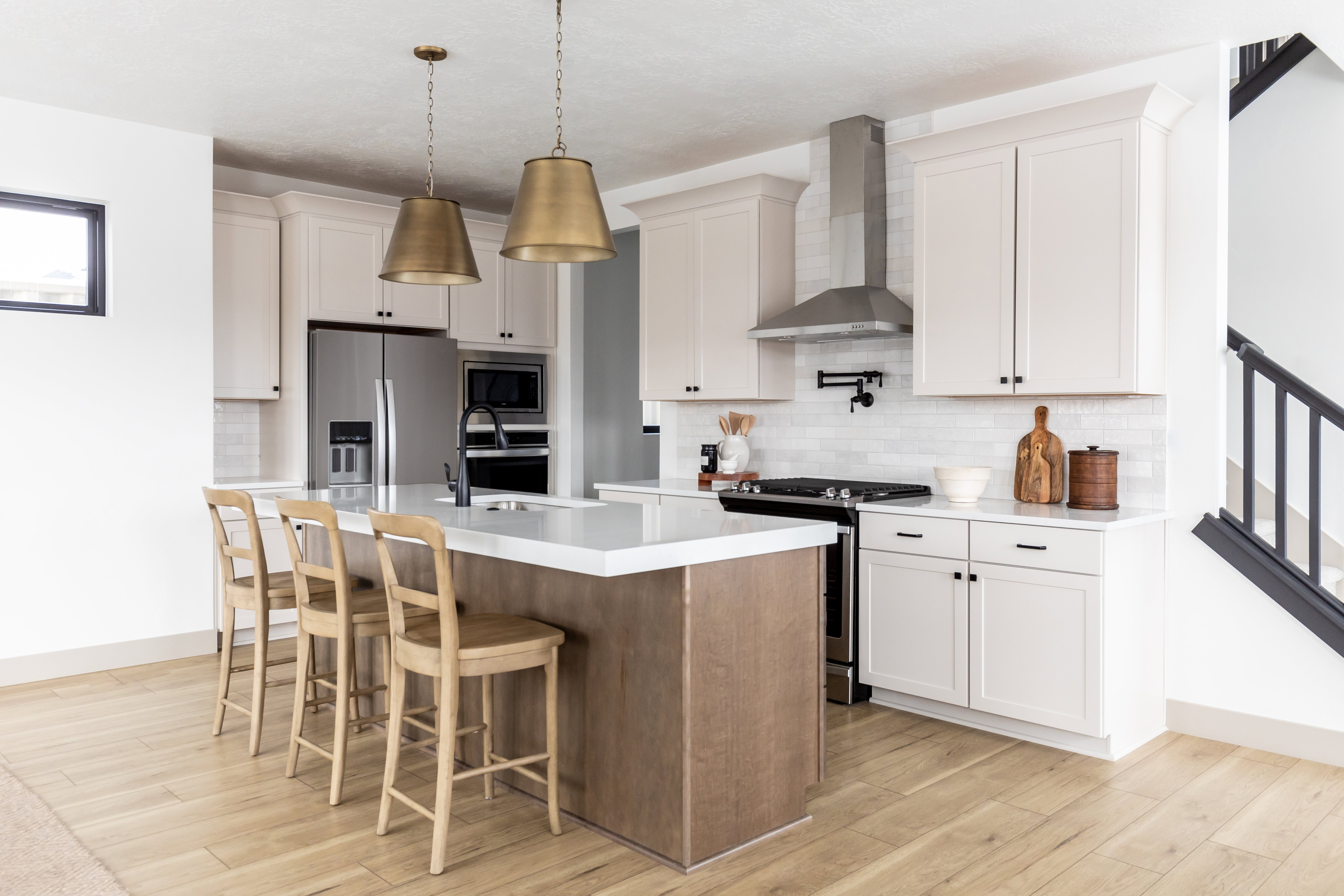 Two tone kitchen with stainless steel appliances, a kitchen bar, light wood finished floors, an island with sink, and two tone cabinets