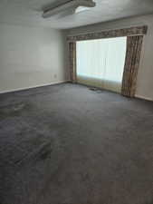 Unfurnished room featuring dark carpet and a textured ceiling