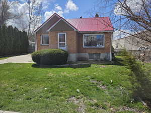 View of side of property featuring a metal roof, brick siding, and a chimney