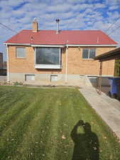 Rear view of property with a metal roof, brick siding, and a chimney