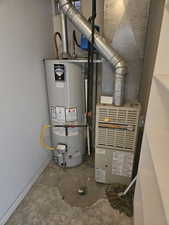 Utility room featuring strapped water heater and heating unit