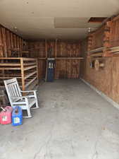 Miscellaneous room with concrete flooring, a garage, and wooden walls
