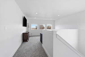 Hallway with light carpet and an upstairs landing