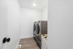 Laundry area with light wood finished floors and washing machine and clothes dryer