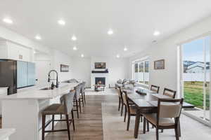 Dining room with a large fireplace, light wood-type flooring, and recessed lighting