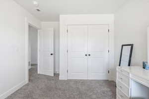 Unfurnished bedroom with light colored carpet and a closet