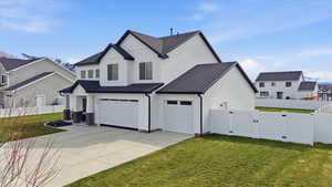 View of property exterior featuring board and batten siding, roof with shingles, a gate, concrete driveway, and a garage