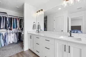 Bathroom featuring double vanity, ensuite bathroom, light wood-style floors, and a spacious closet