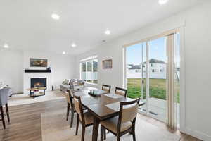 Dining space featuring light wood finished floors, recessed lighting, and a fireplace