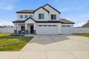 View of front facade with a gate, a porch, concrete driveway, board and batten siding, and a garage