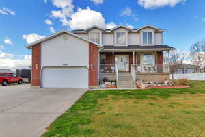 View of front facade with a porch, brick siding, concrete driveway, and an attached garage