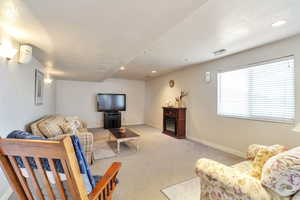 Living room with light carpet, a glass covered fireplace, recessed lighting, and a textured ceiling