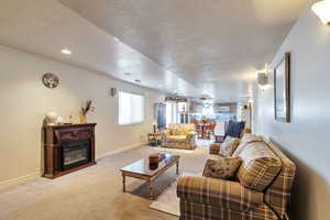 Carpeted living area with a textured ceiling, recessed lighting, and a glass covered fireplace