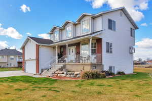Traditional-style house with a porch, a front yard, driveway, and brick siding