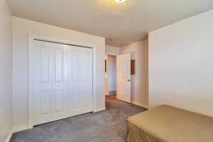 Bedroom with dark colored carpet and a closet