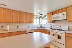 Kitchen featuring white appliances, light countertops, light wood finish cabinets, and light tile patterned floors