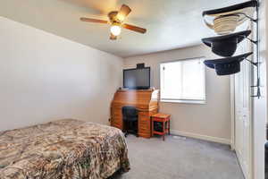 Bedroom with light carpet, a textured ceiling, and ceiling fan