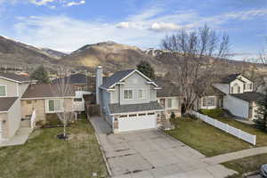 View of front facade featuring an attached garage, driveway, a chimney, a mountain view, and roof with shingles