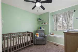 Carpeted bedroom with a nursery area and ceiling fan