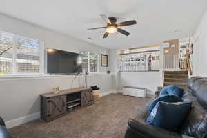 Carpeted living room with baseboards and ceiling fan