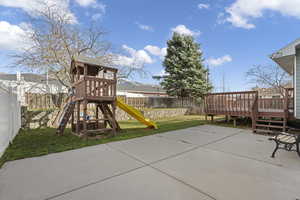 View of playground featuring a fenced backyard, a patio, and a wooden deck