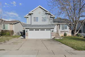 View of front facade with brick siding, a front yard, concrete driveway, an attached garage, and a shingled roof
