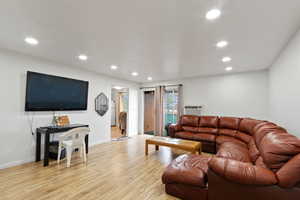 Living room with light wood finished floors and recessed lighting