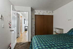 Bedroom featuring a closet, carpet, and a textured ceiling