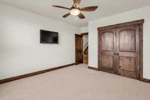 Unfurnished bedroom featuring light colored carpet, a ceiling fan, and a closet