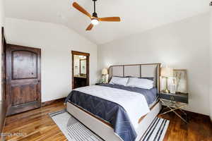 Bedroom featuring lofted ceiling, wood finished floors, ensuite bath, and ceiling fan