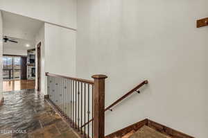 Stairs featuring stone tile floors, a fireplace, and a ceiling fan