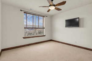 Carpeted spare room featuring baseboards and a ceiling fan