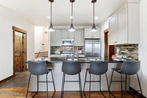 Kitchen with a peninsula, a kitchen bar, stainless steel appliances, pendant lighting, and dark stone counters