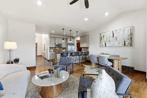 Living room with light wood-style flooring, ceiling fan, vaulted ceiling, and recessed lighting