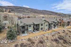 Back of property featuring board and batten siding, a patio, a mountain view, stone siding, and a balcony