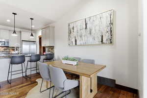 Dining space featuring dark wood-style floors, recessed lighting, and vaulted ceiling