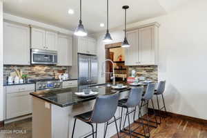 Kitchen with a peninsula, stainless steel appliances, a kitchen breakfast bar, hanging light fixtures, and decorative backsplash