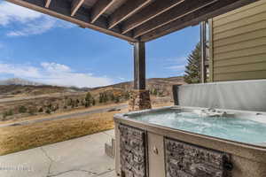 View of patio with a hot tub and a mountain view