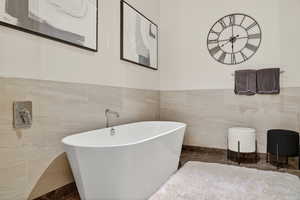 Bathroom featuring tile walls, wainscoting, and a freestanding tub