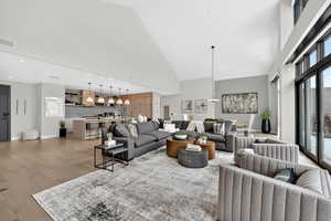 Living room featuring a high ceiling, light wood finished floors, and suspended lighting