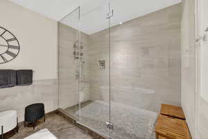 Master bathroom with tile walls, a stall shower, and a wainscoted wall