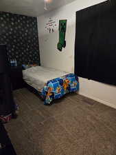 Bedroom with dark carpet and wallpapered walls