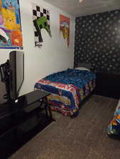 Bedroom featuring wallpapered walls and dark carpet