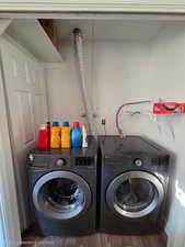 Laundry area featuring independent washer and dryer and wood finished floors