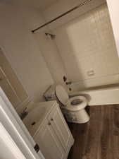 Full bath with vanity, dark wood-style floors, and shower / bath combination