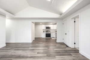 Unfurnished living room with lofted ceiling and dark wood-style floors