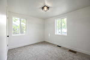 Carpeted spare room featuring baseboards