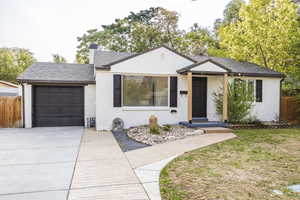 View of front facade featuring brick siding, an attached garage, driveway, a chimney, and a shingled roof